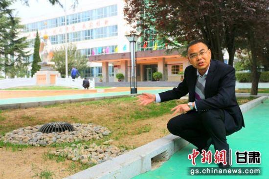 图为庆阳市团结小学校长齐建伟向记者介绍改造后的低洼雨水井。 