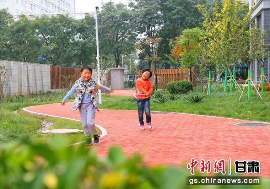 图为庆阳当地小朋友正在改造后的小区花园里嬉戏打闹。